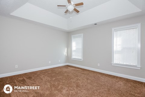 the living room of a new home with a carpet and a ceiling fan