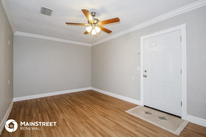 the living room of a home with a ceiling fan and wood floors