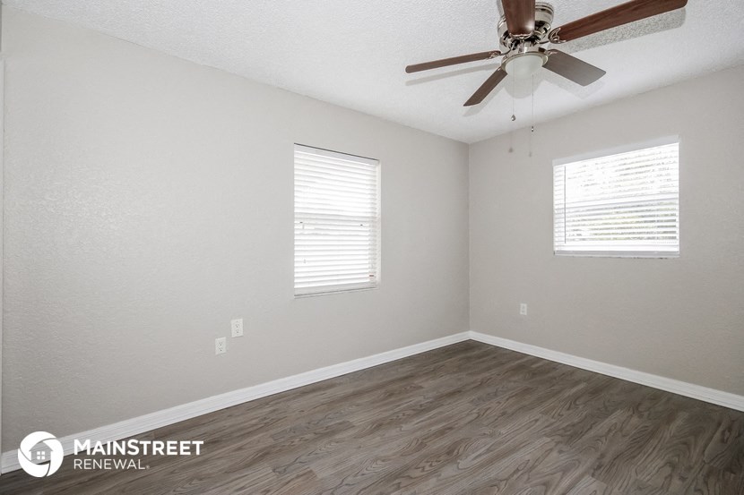 the spacious living room with ceiling fan and wood flooring