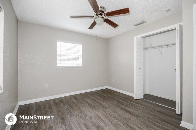 the spacious bedroom has a ceiling fan and a closet