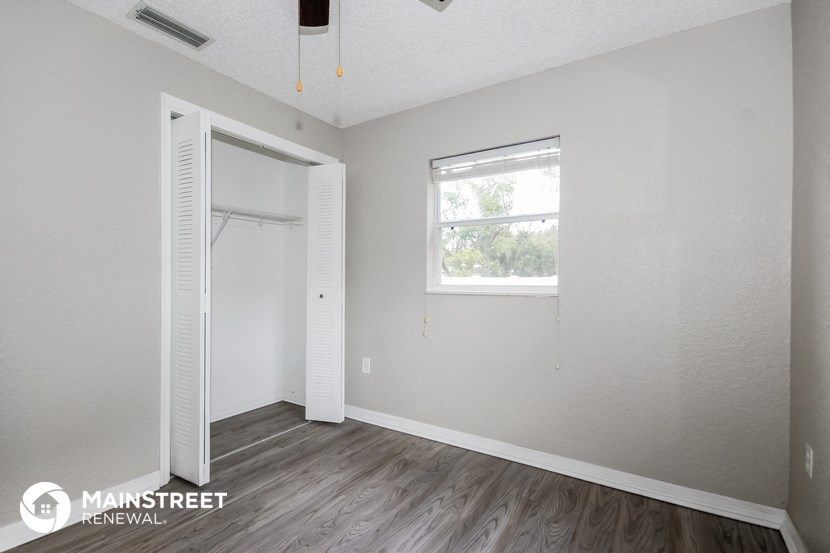 the interior of a white bedroom with a closet and a window