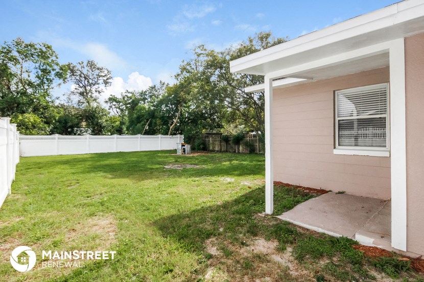 the backyard of a home with a lawn and a white fence