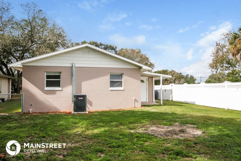 a small pink house with a yard and a white fence