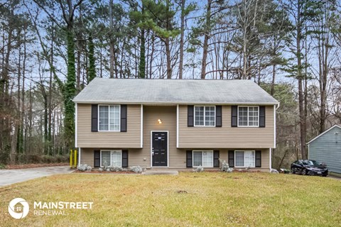 front view of a tan house with a yard and trees
