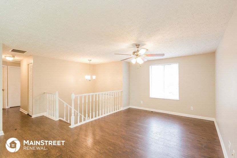the living room of an empty house with a ceiling fan