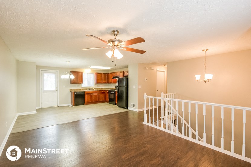the living room and kitchen of an empty house with a ceiling fan