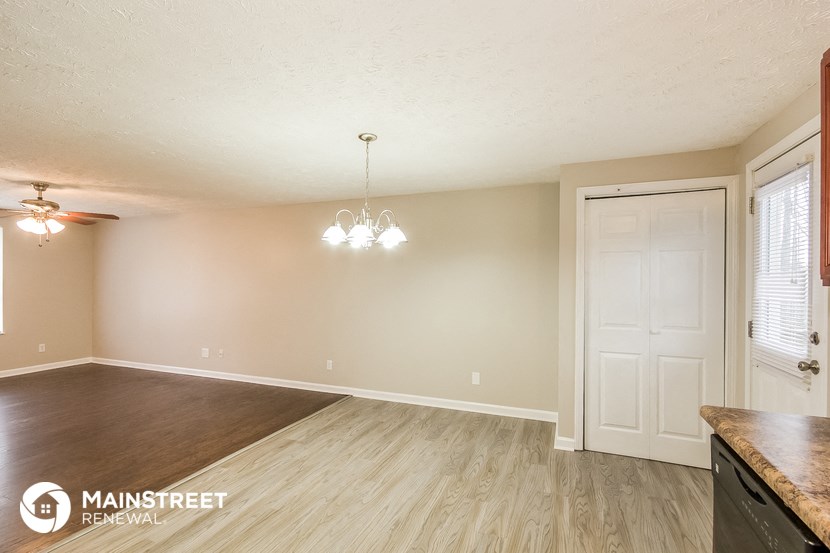 the living room and dining room with wood flooring and a white door