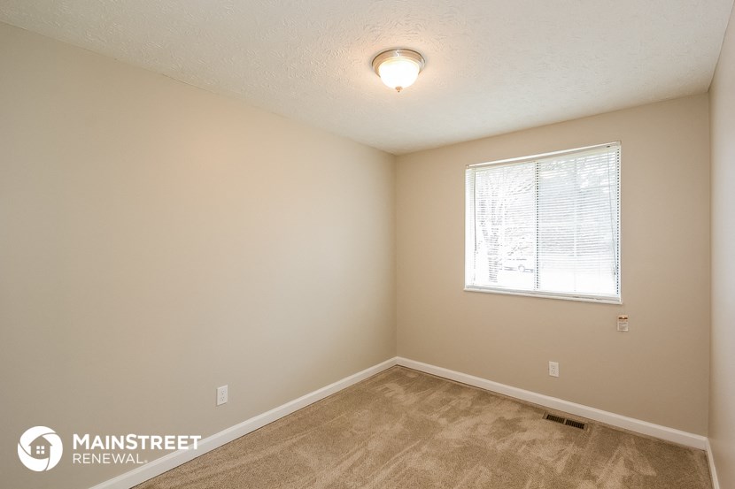 the spacious bedroom of this 2500sf home has carpeted floors and a window