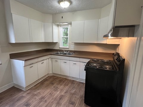 an empty kitchen with white cabinets and a stove