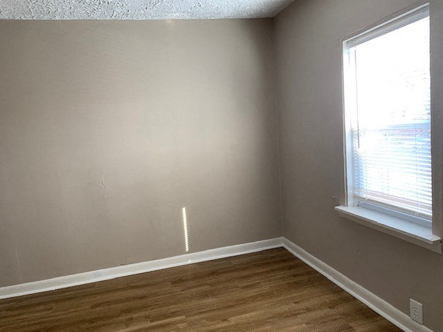 an empty room with a window and wooden floors