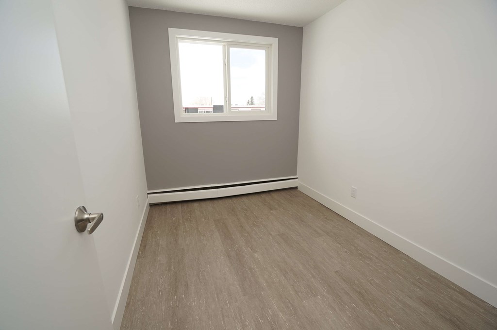 a empty room with a window and wooden floors