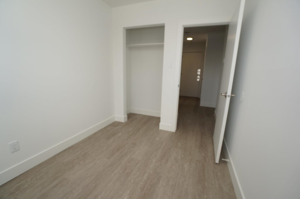 an empty room with a hallway and a door to a closet