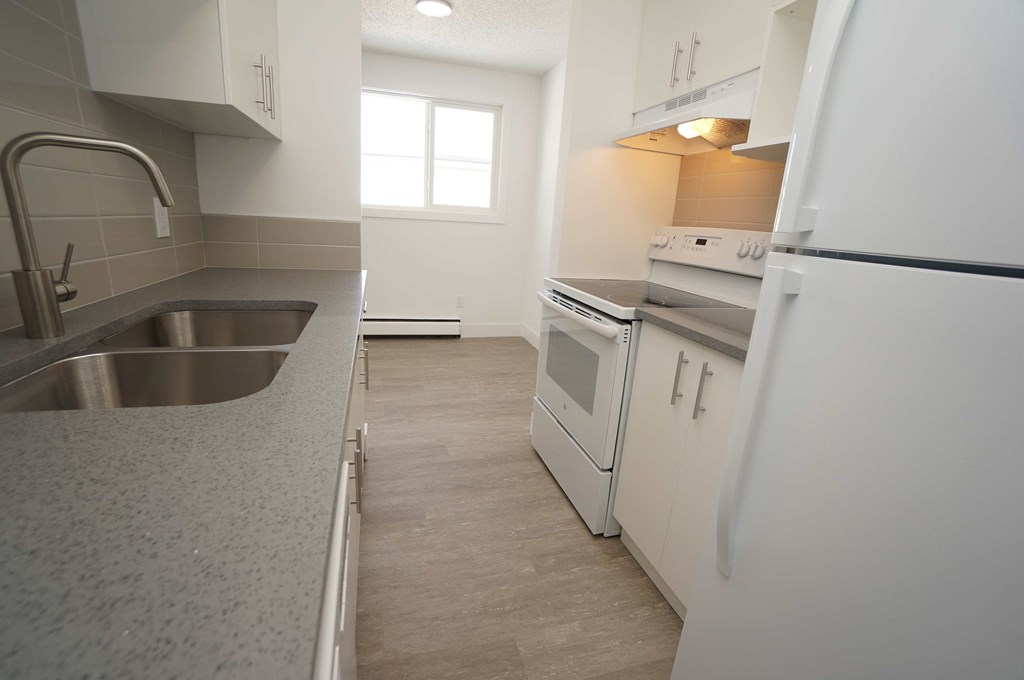 a kitchen with white cabinets and a sink and a refrigerator