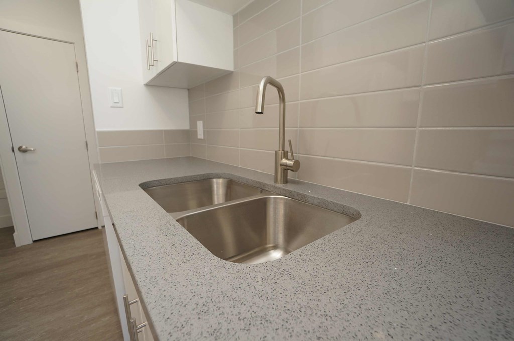 a stainless steel sink in a quartz counter top in a kitchen