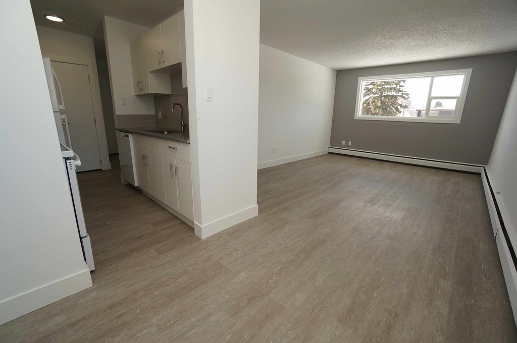 an empty living room and kitchen with wood floors