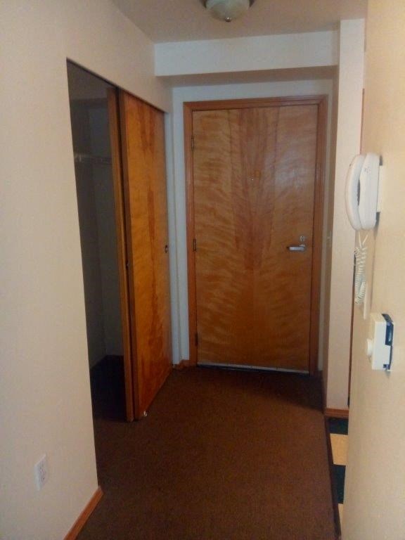 a hallway with a wooden door and a phone on the wall