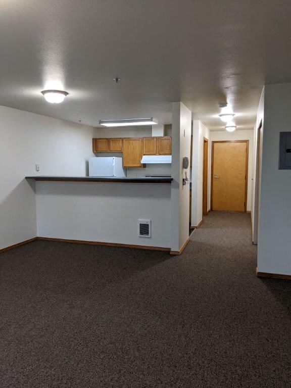 an empty room with a kitchen and a hall way