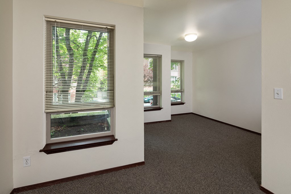 a living room with a large window and a carpeted floor