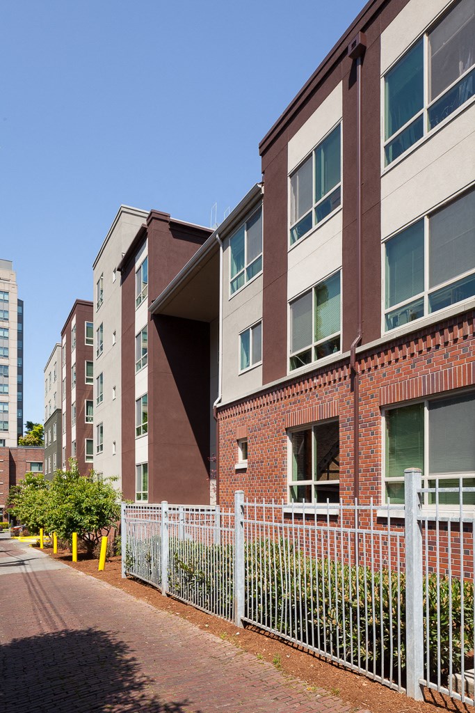a row of brick apartment buildings with a white fence