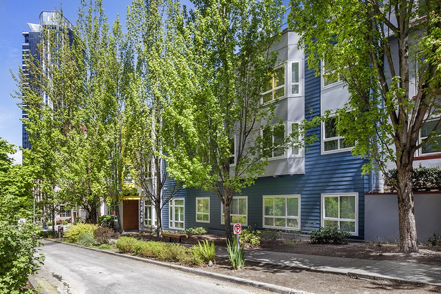 a street view of a blue house with green trees