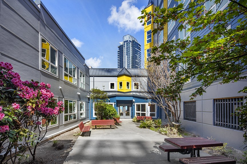 a courtyard with benches and buildings in the background