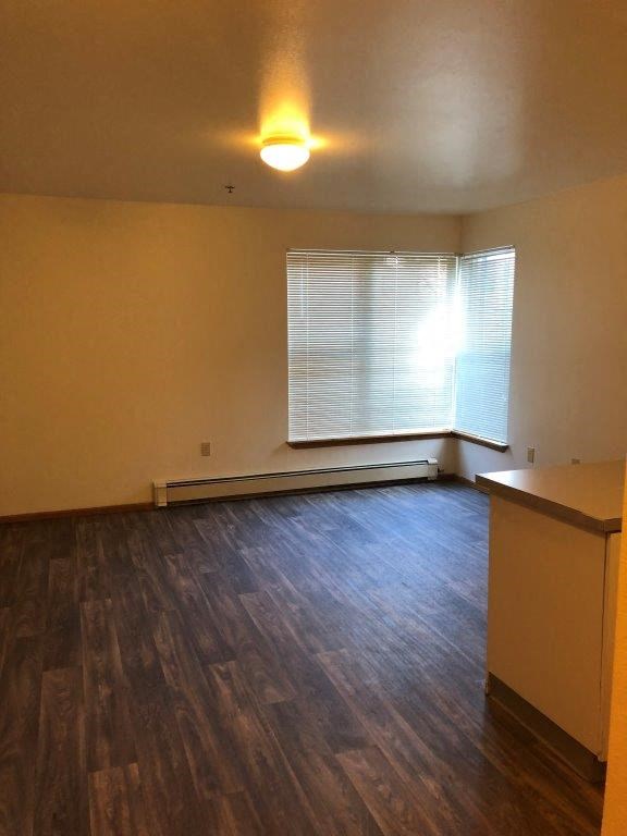 an empty living room with a window and wooden floors