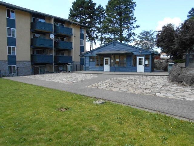 an apartment building with a cobblestone sidewalk and a lawn