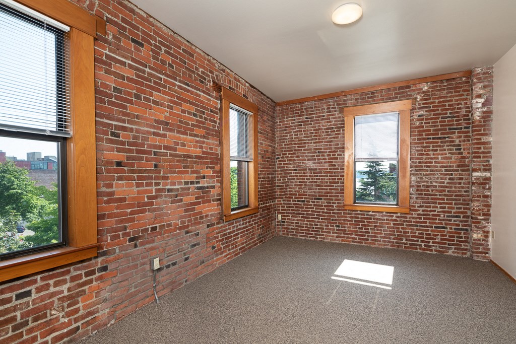 a living room with a brick wall and two windows