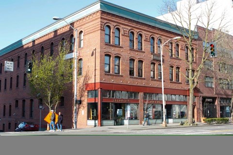 A red brick building with a green roof and a tree in front of it.
