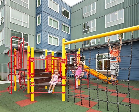 Children playing on a playground with a red and yellow structure.