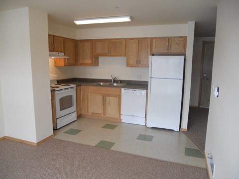 A kitchen with white appliances and wooden cabinets.