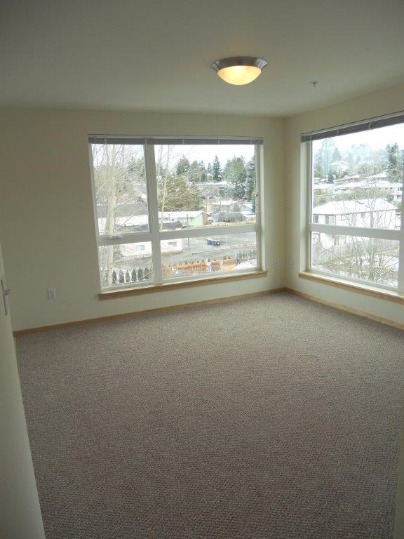 an empty living room with three large windows