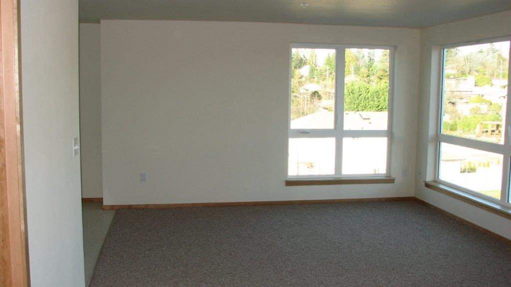 an empty living room with three large windows