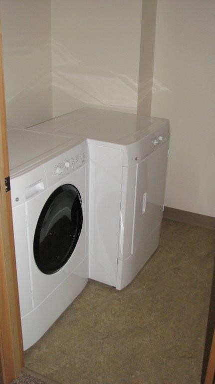 Two white front loading washing machines in a laundry room.