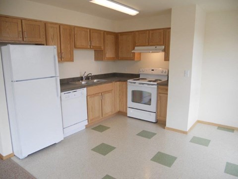 A kitchen with white appliances and wooden cabinets.