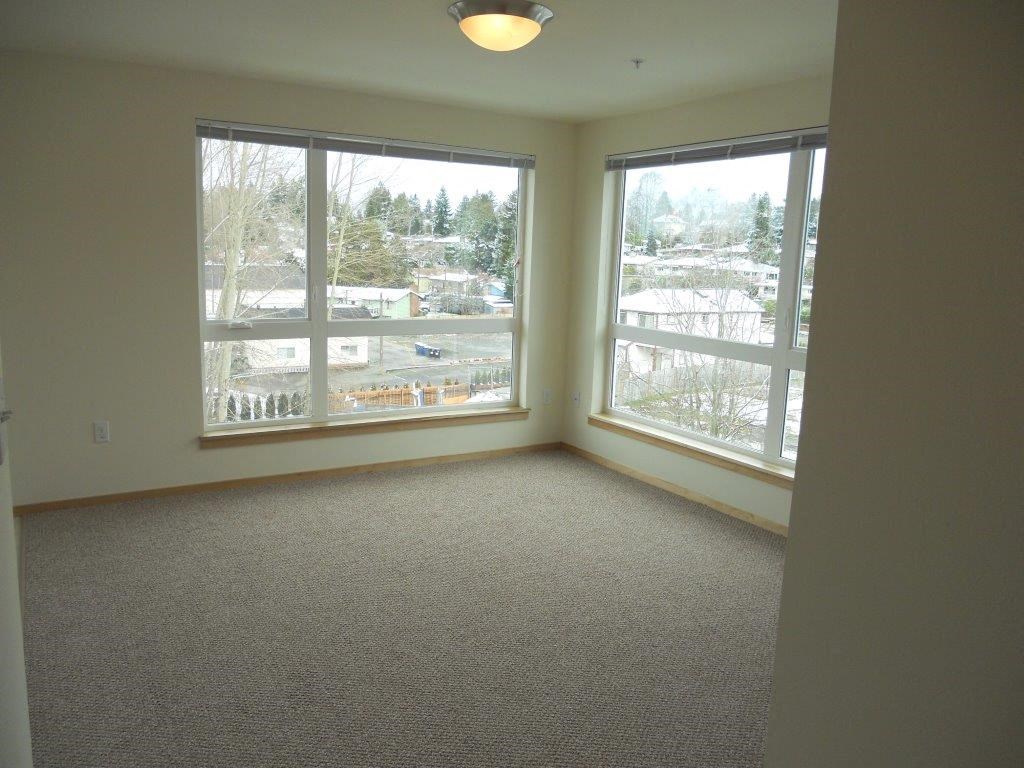 an empty living room with three large windows