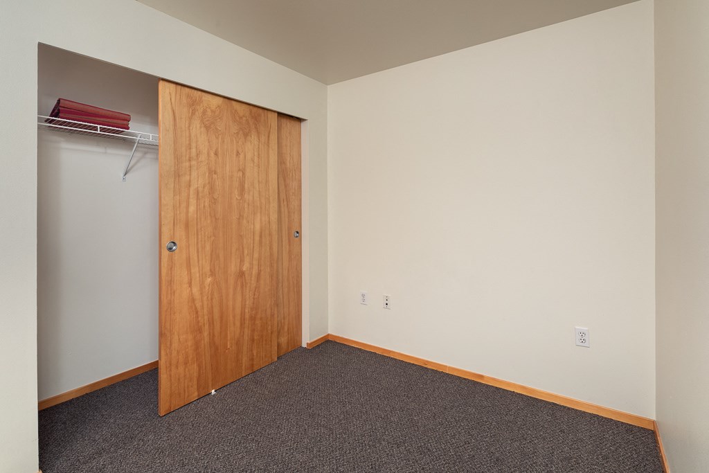 A room with a brown door and grey carpet.
