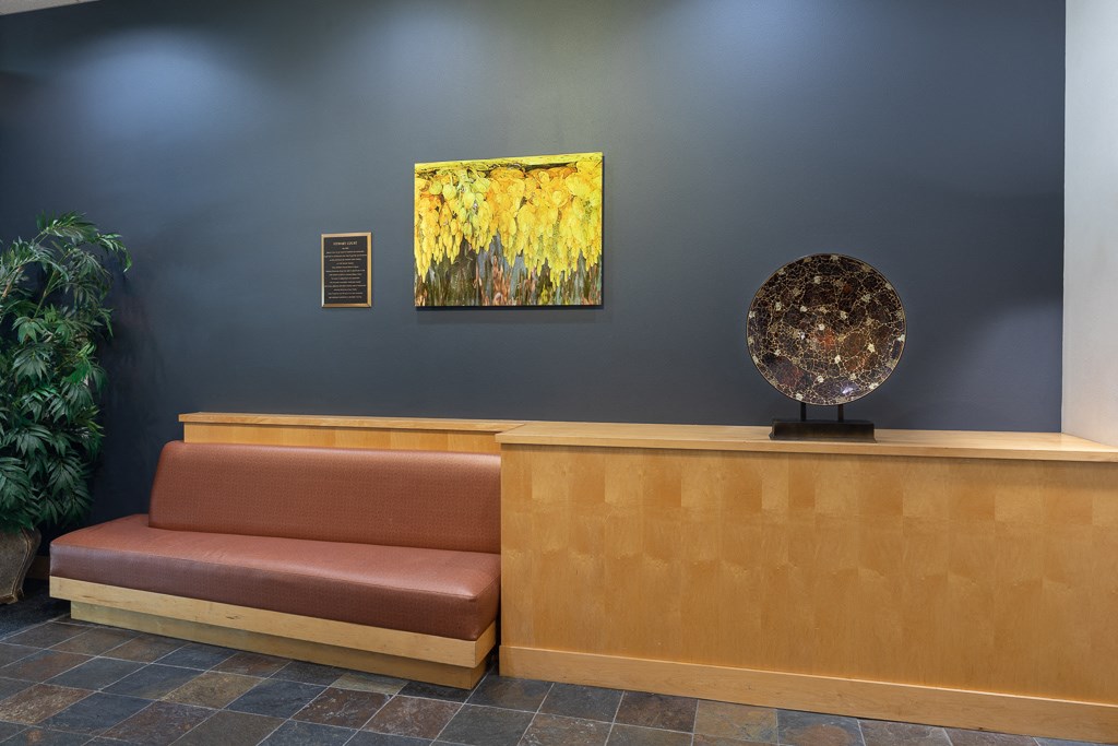 A brown couch sits in front of a painting and a sculpture.