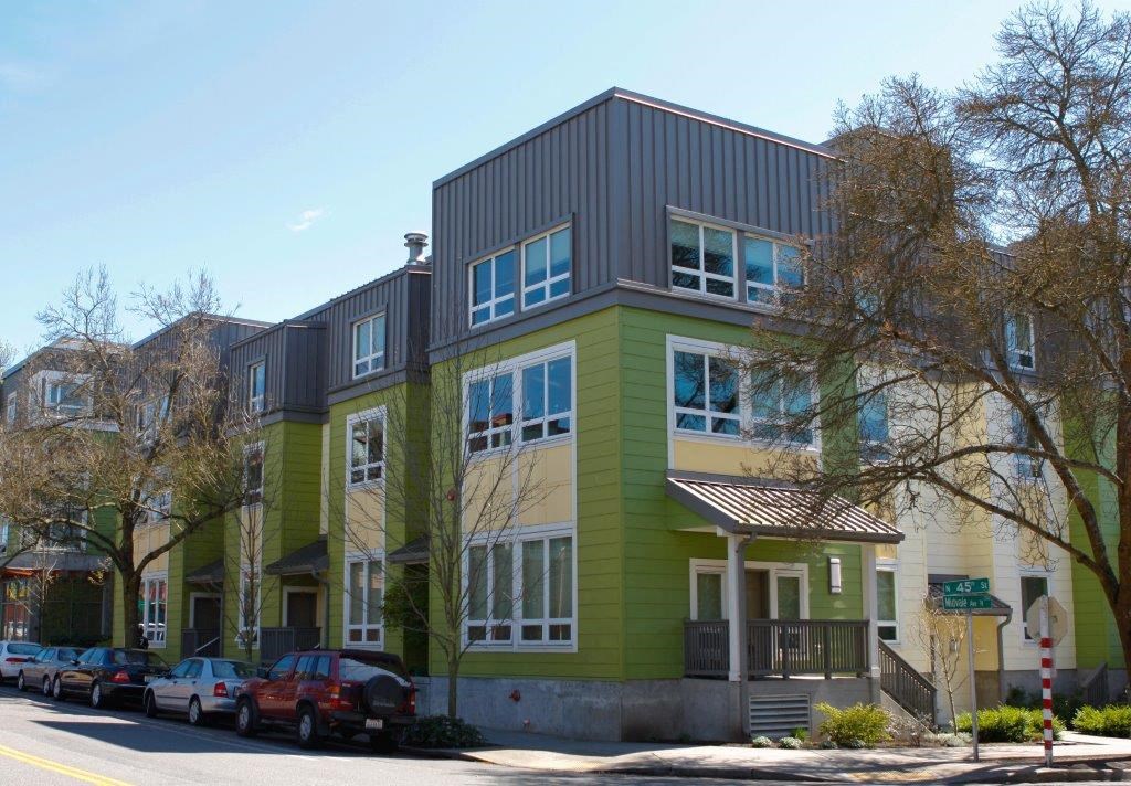 a green and yellow house with cars parked in front of it