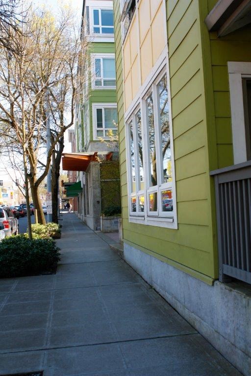an empty sidewalk next to a green building