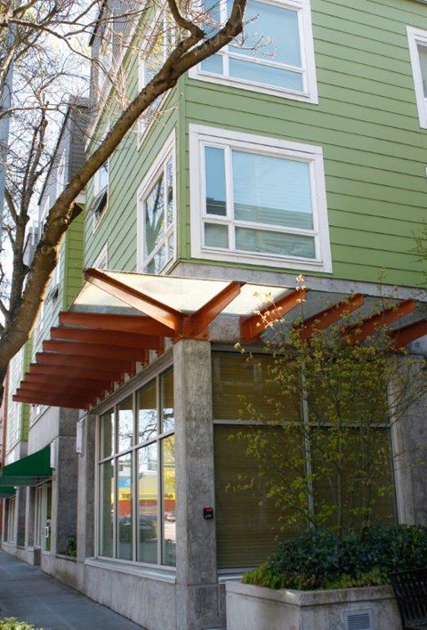 a green house with a tree in front of it