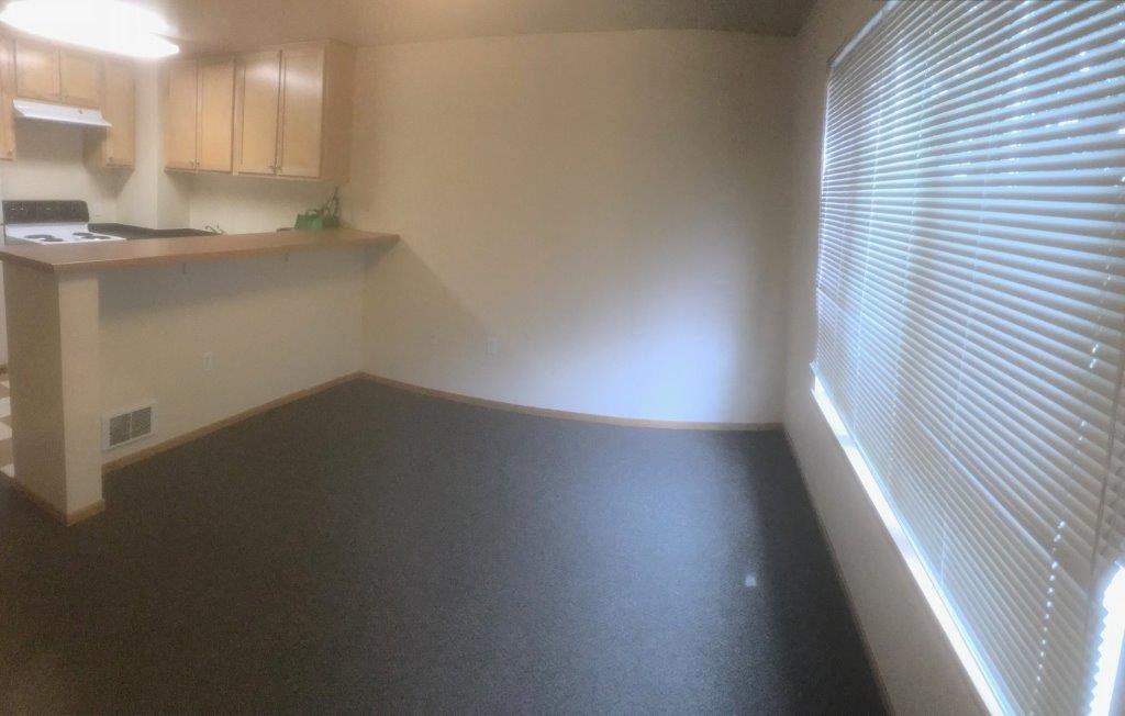 an empty room with a window and a kitchen