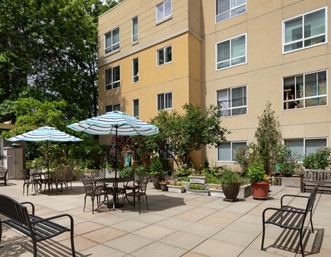 a patio with tables and umbrellas in front of a building