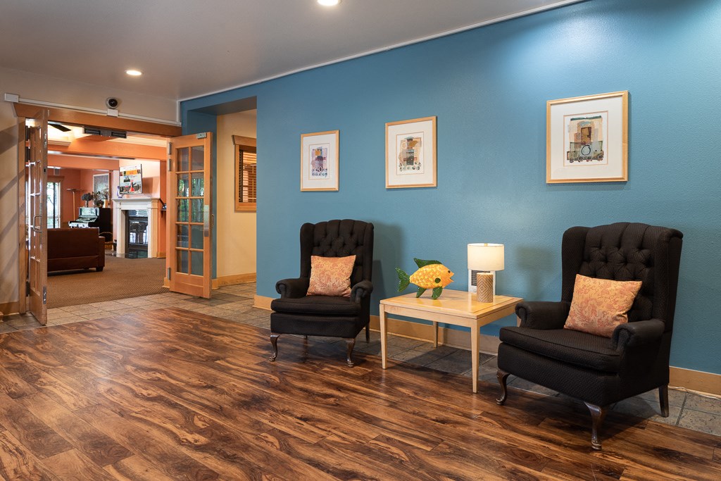 a living room with two black chairs and a blue wall