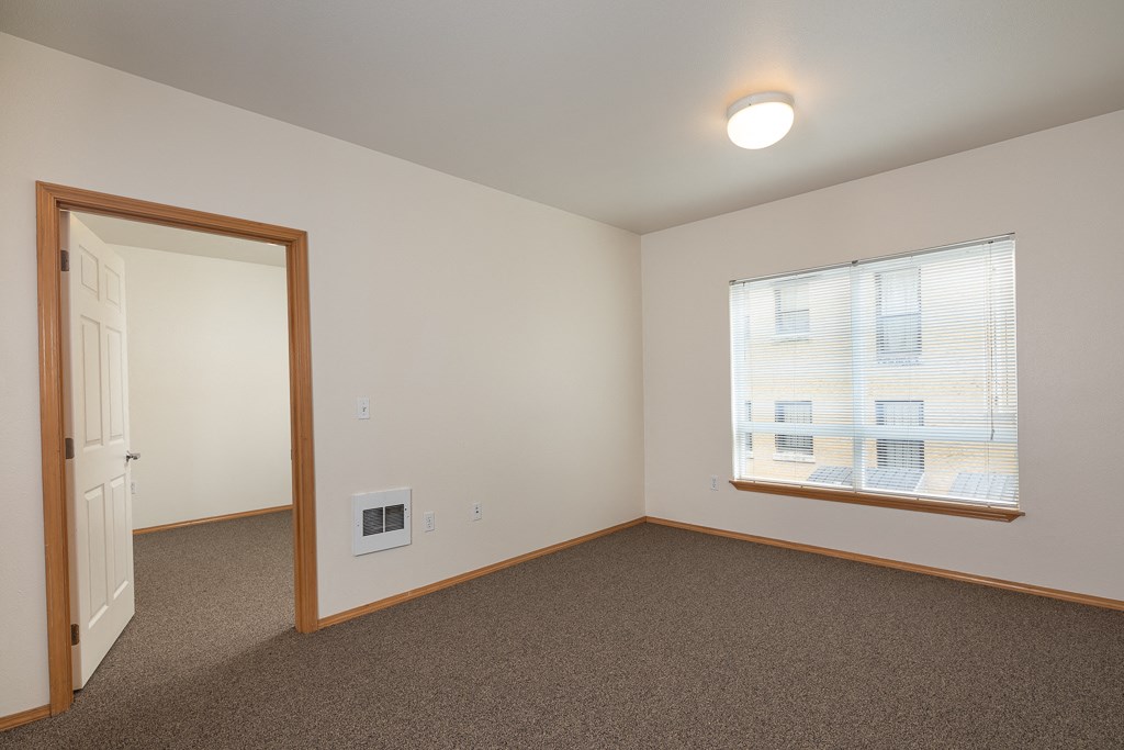 an empty living room with a window and a door