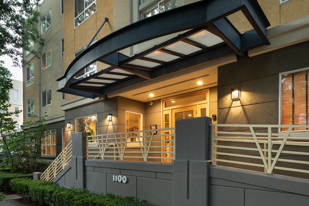 the entrance to a condo building with stairs and a balcony