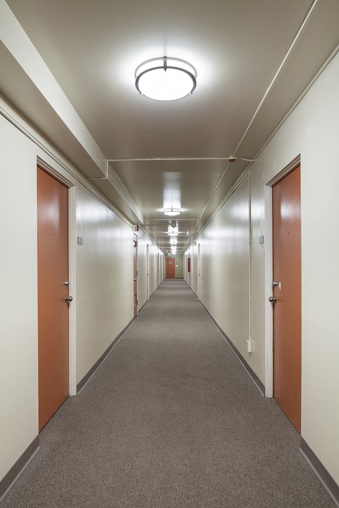 a long corridor with doors and white walls and a carpeted floor