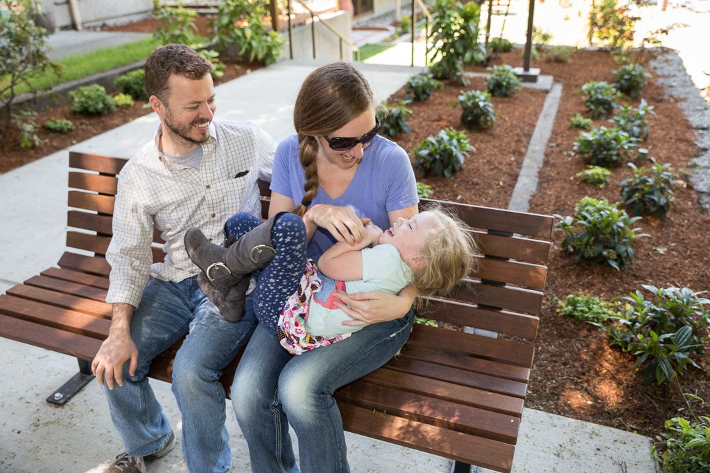 a man and woman sitting on a park bench with a child
