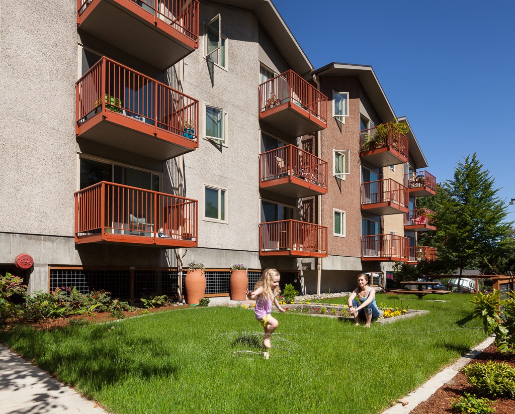 two girls play in the grass in front of an apartment building