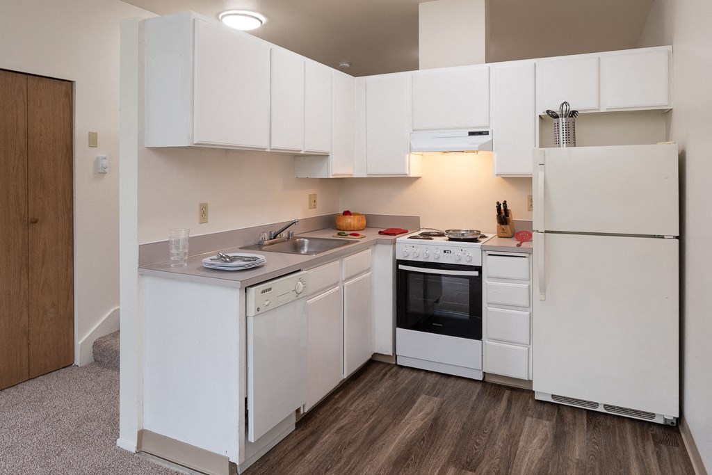 an empty kitchen with white cabinets and appliances and a refrigerator